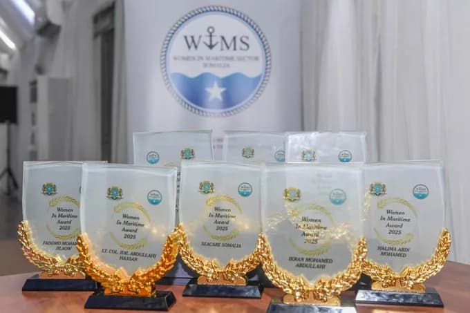 Glass Women in Maritime Award 2025 trophies on a table, in front of the Women in Maritime Sector Somalia logo