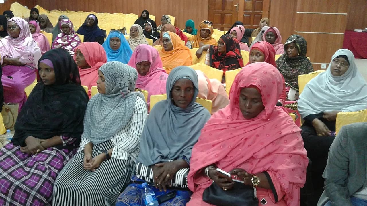 A hall full of women in colourful headscarves, seated together for a session
